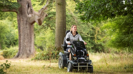 PMV user riding on a trail through trees